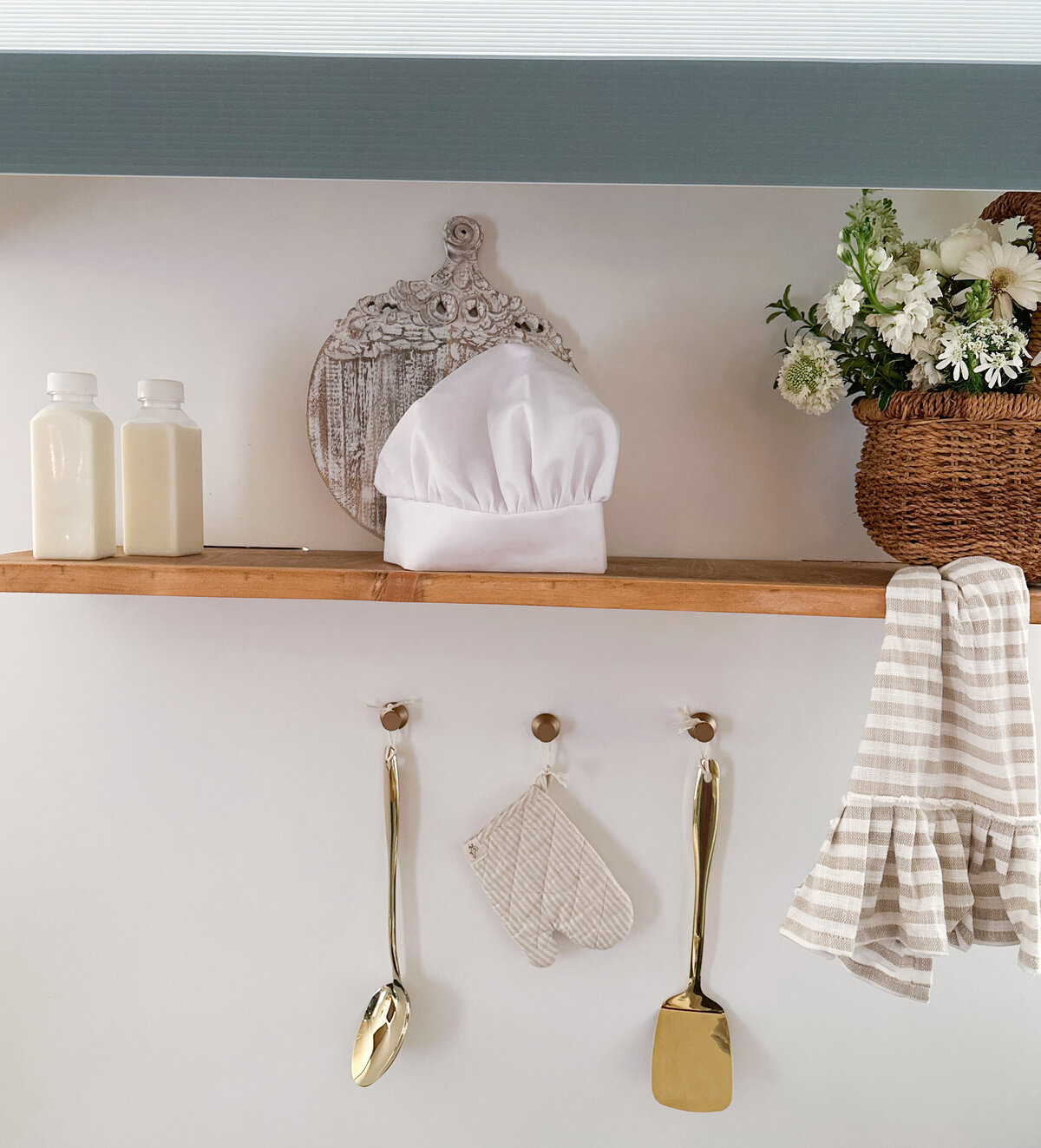 Shelves on a bakery wall with a chef hat, oven mitt and kids decorations. 