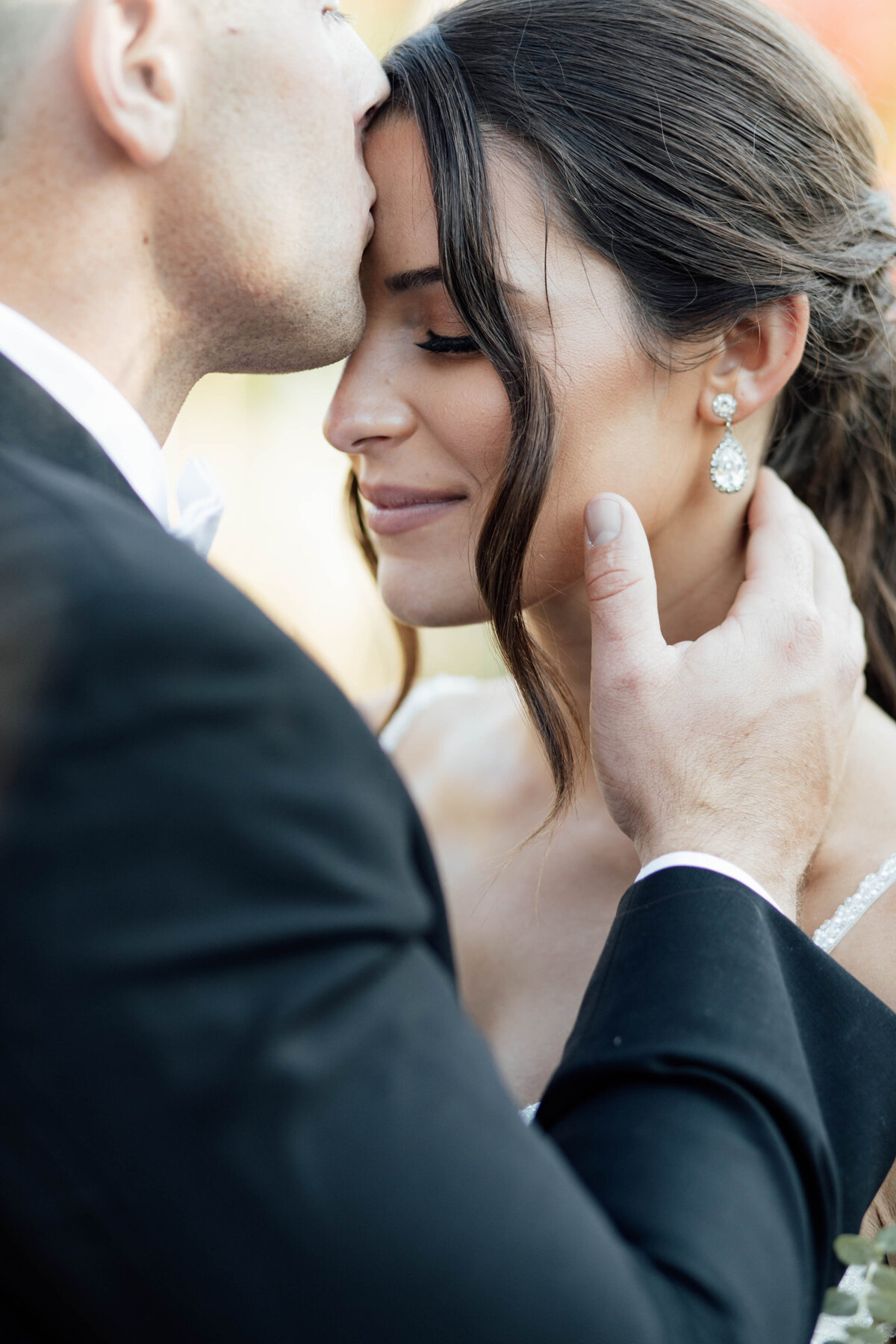 Groom kissing bride on her forehead. 