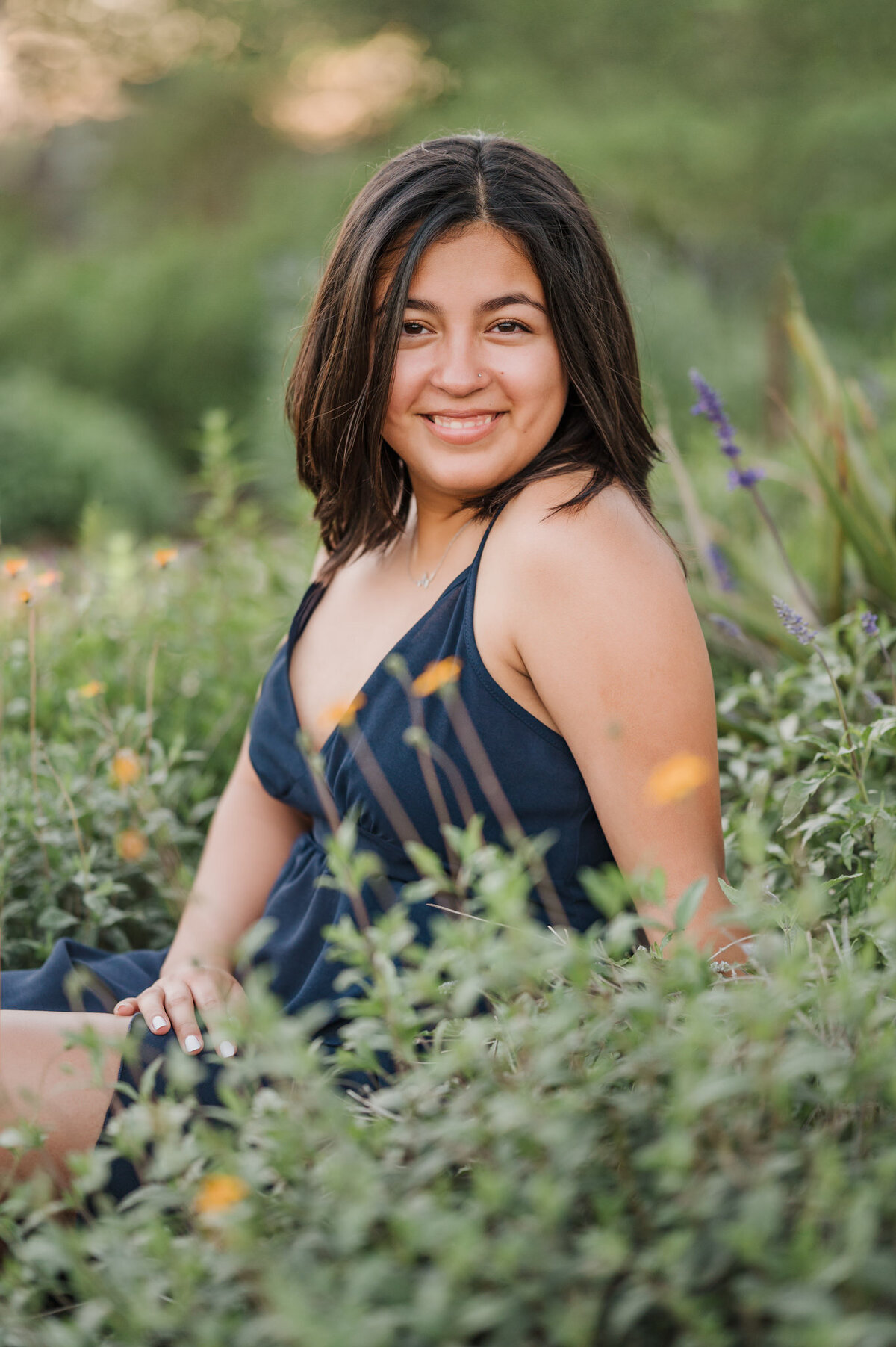 Girl sits among the flowers during senior pictures in San Antonio.