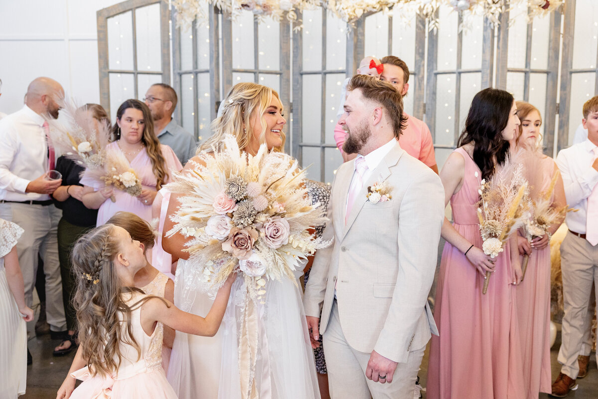 The bride and groom share a joyful moment immediately after their ceremony, looking at each other with love. The bride’s stunning bouquet of dried florals complements the warm tones of the wedding party’s attire