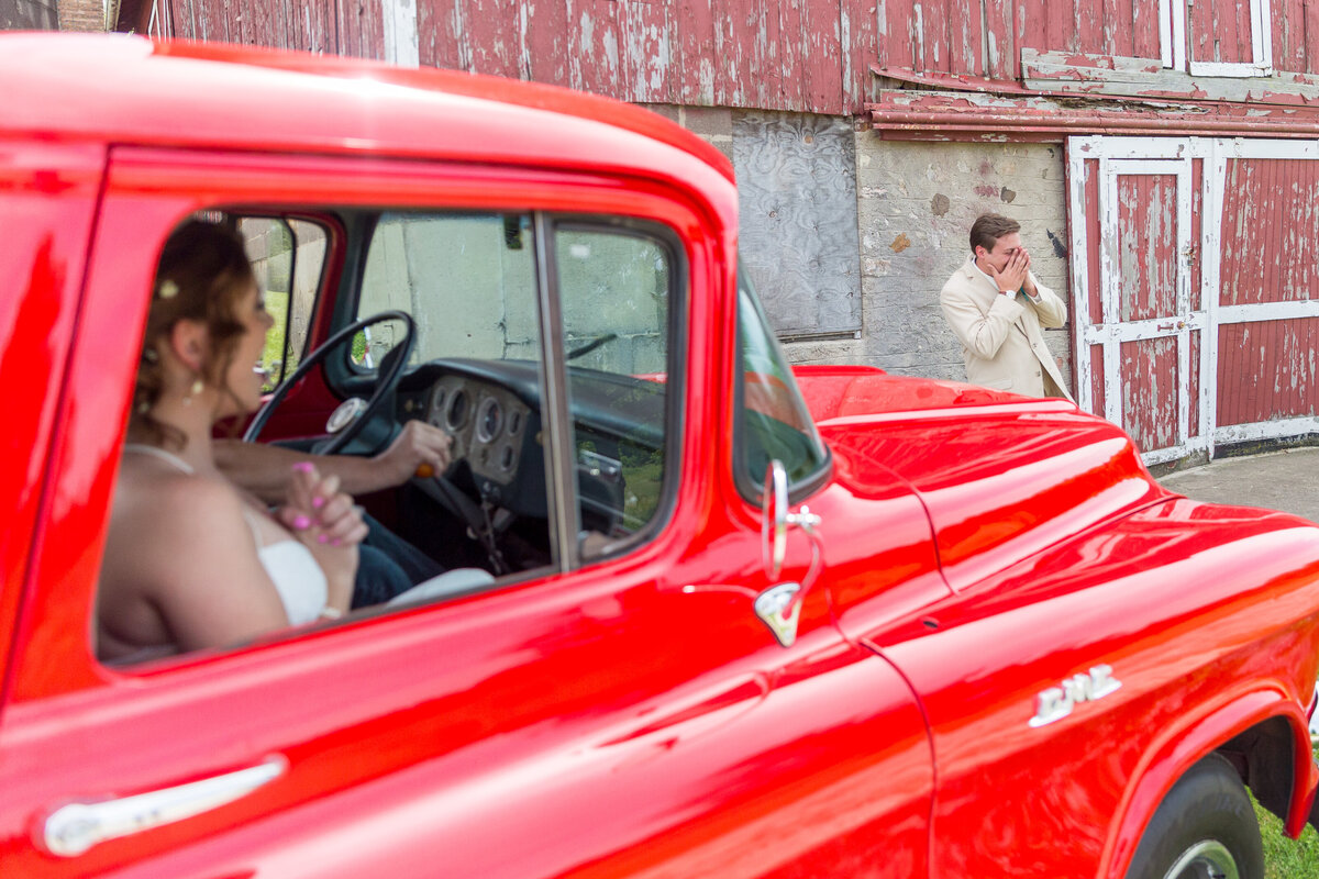 The bride surprises the groom with a red pickup truck during their first look.