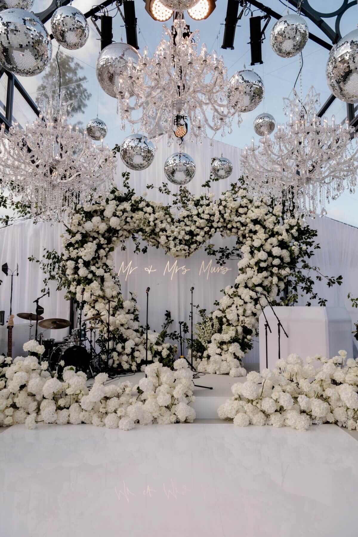 Amelia & Olly Murs wedding stage for band with a heart made out of flowers and white flowers along the ground