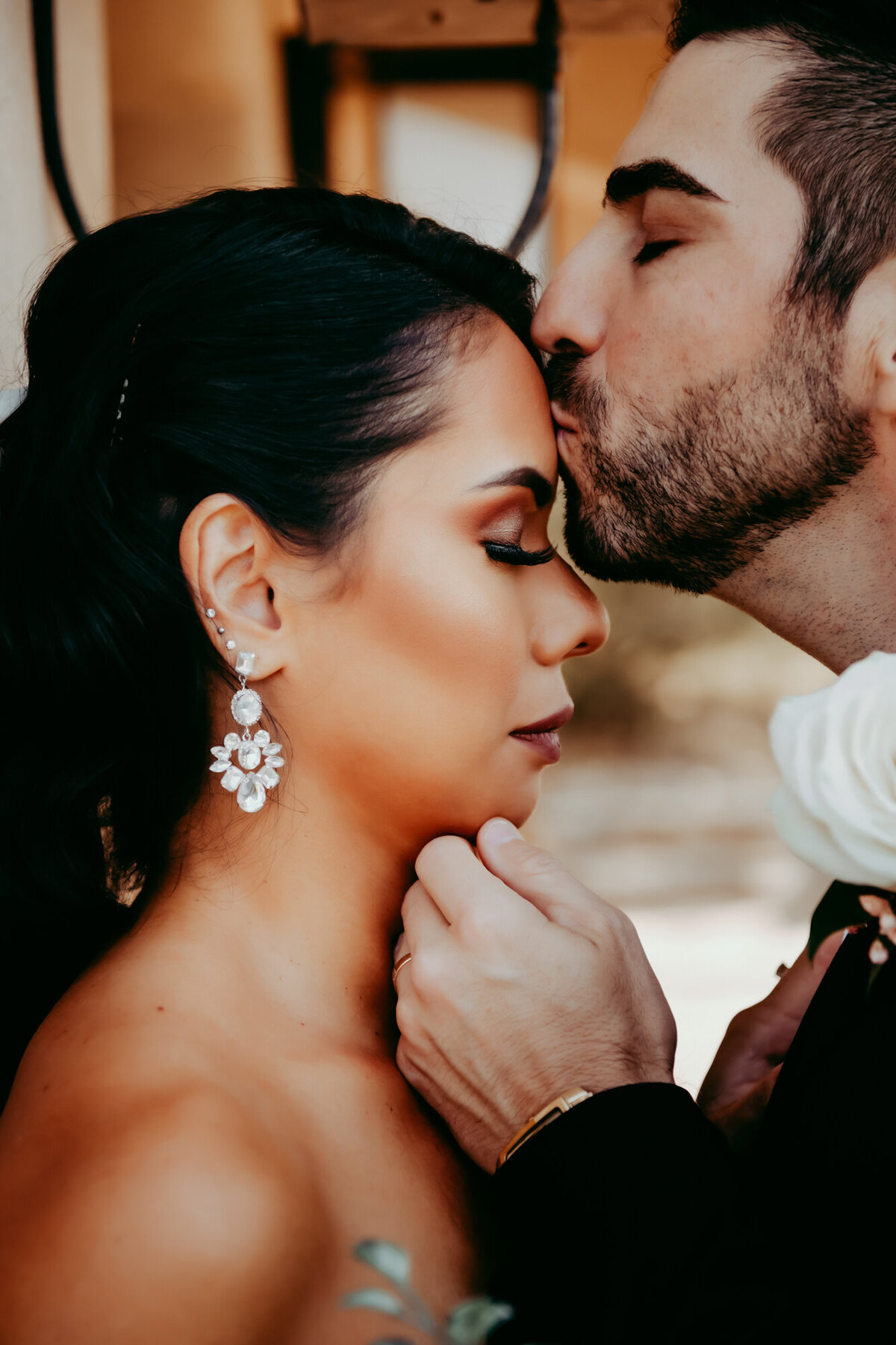 Couples Photography, a groom brings hands u to brides face tenderly and kisses her on forehead