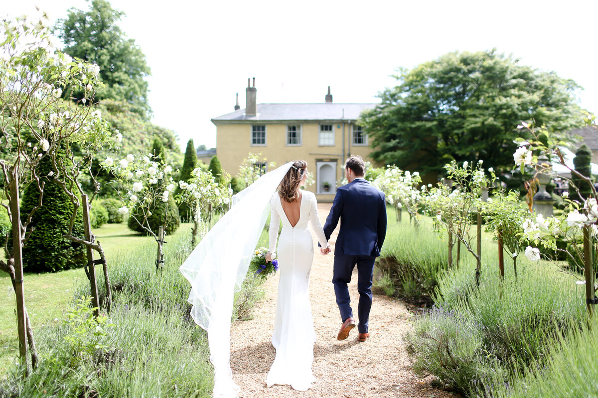 bride-and-groom-walking-down-path-of-lavender-at-luxury-wedding-in-berkshire