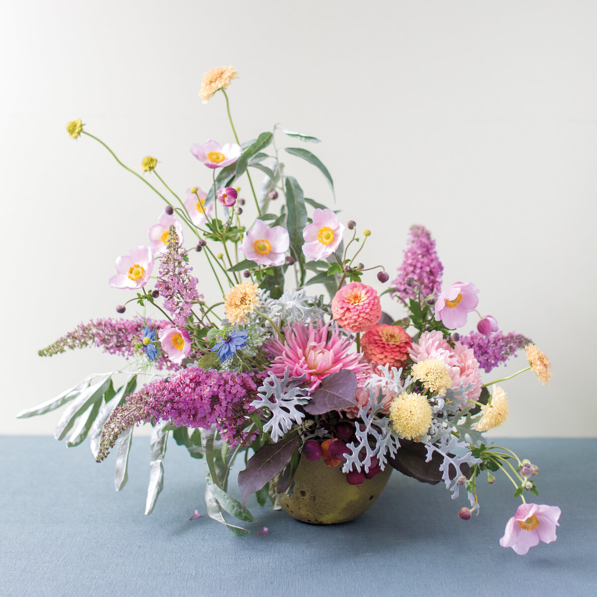 Lilacs, poppies, and spring flowers with lush greenery in a floral wedding arrangement. 