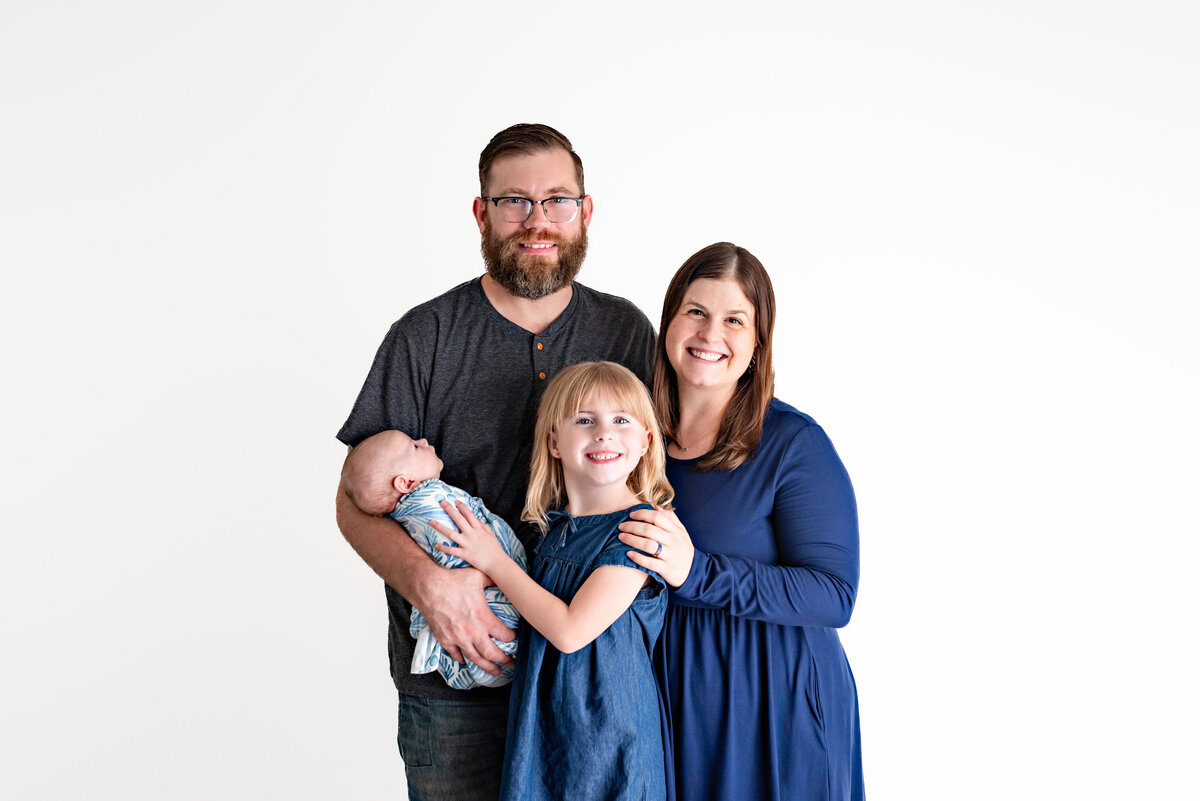 A mom and dad  pose with their little girl and baby boy for family photos in a studio in Hampton Cove Alabama
