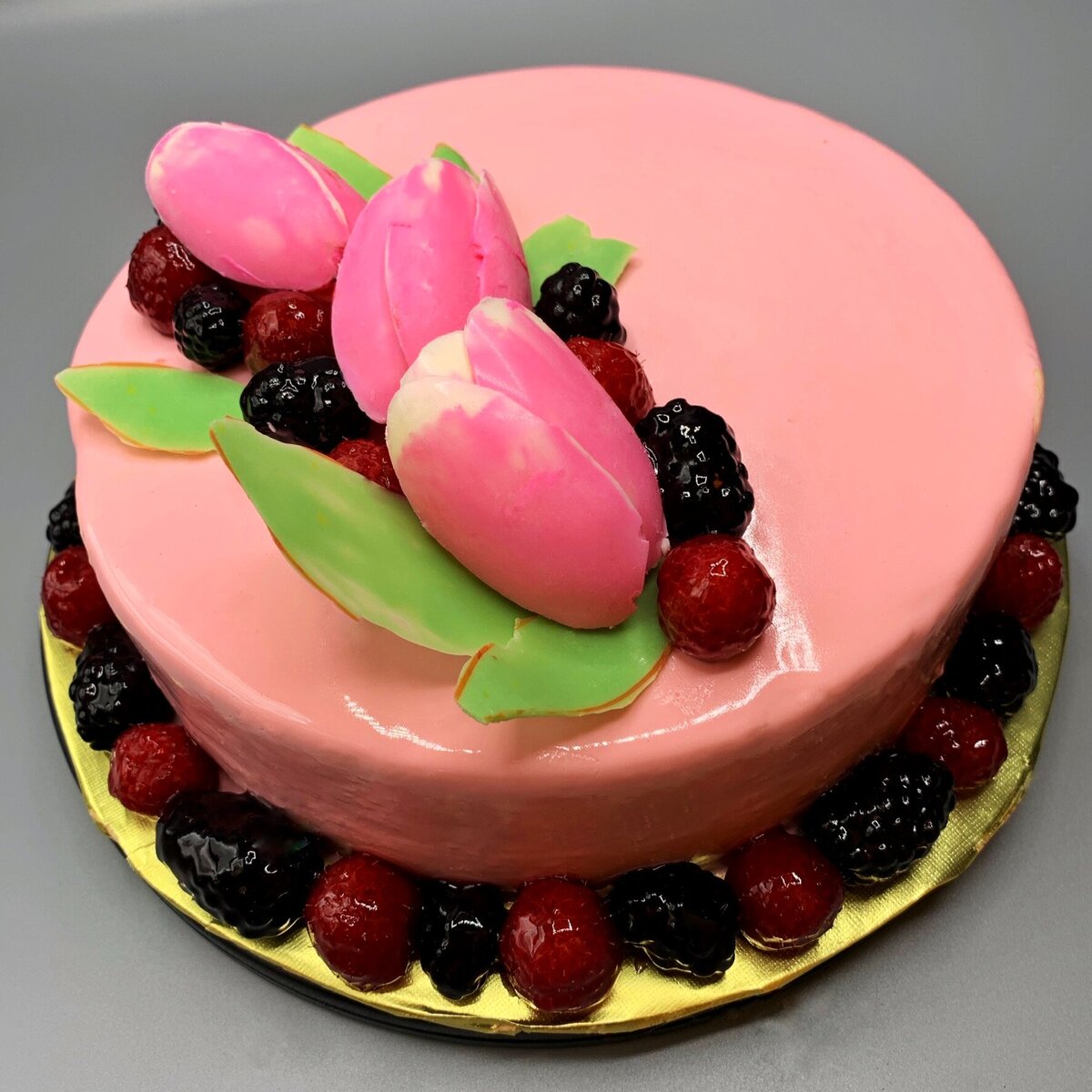 Blackberry mousse filled cake with  shiny pink glaze , fresh berries, and pink chocolate tulips