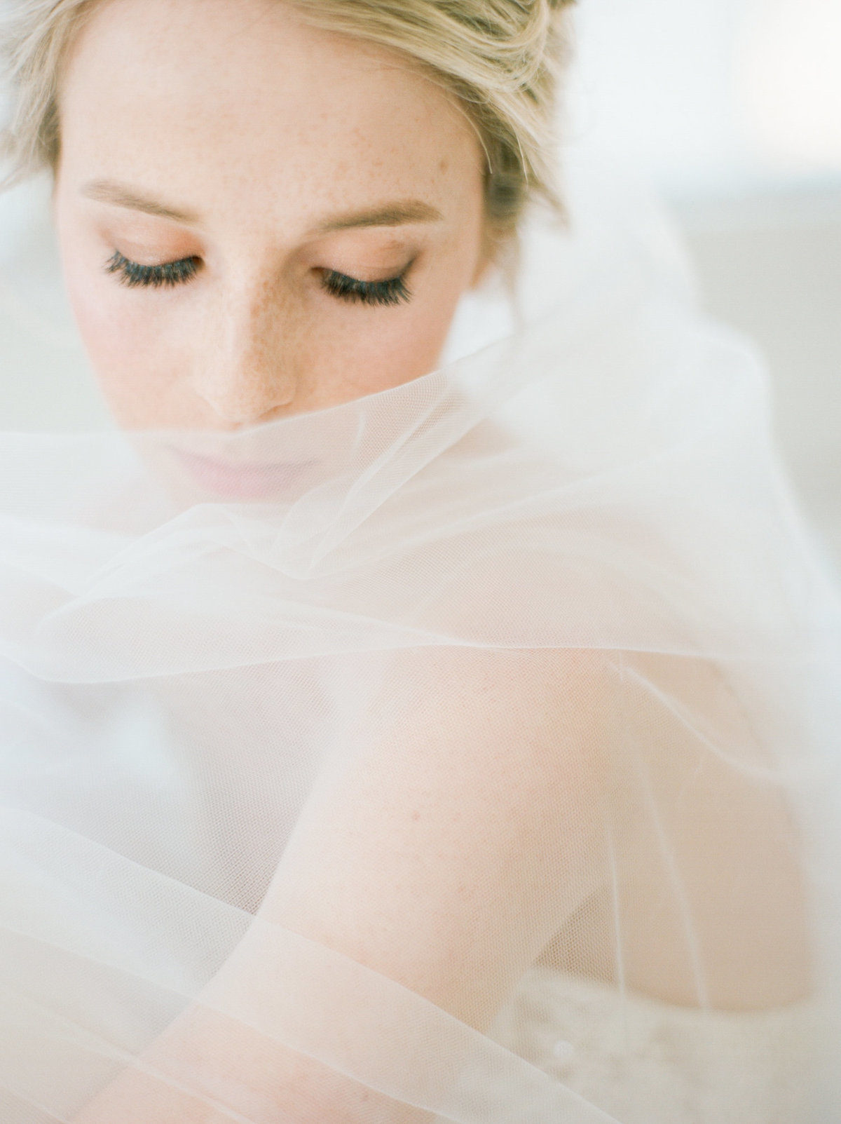 bride wrapped in veil softly lit