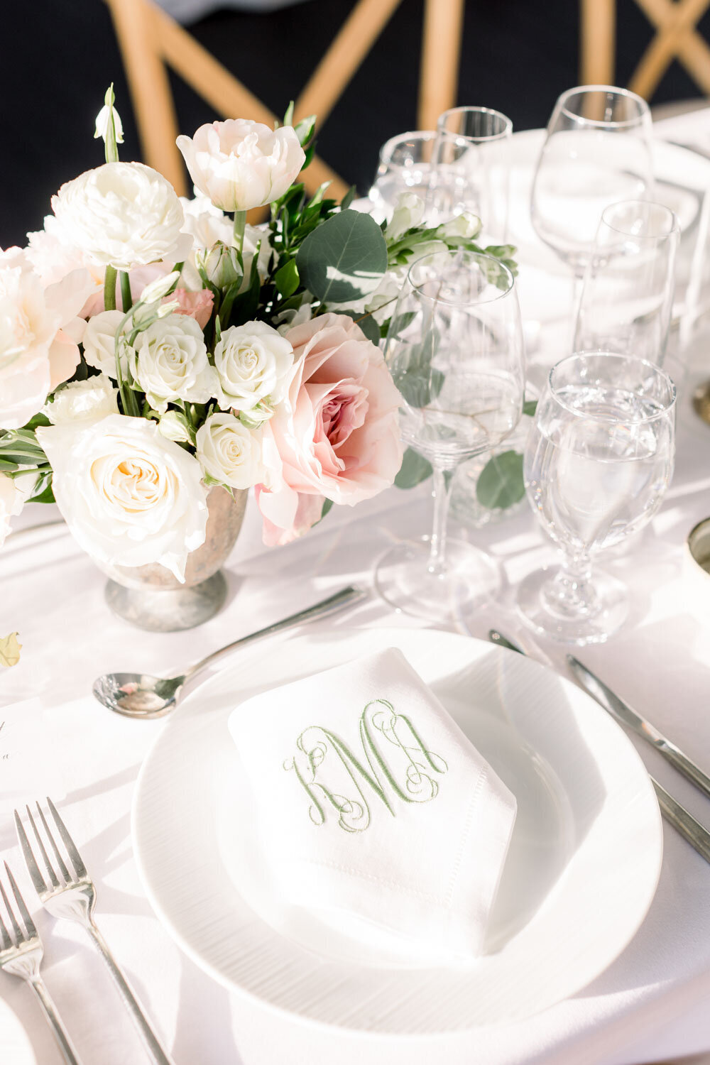 Elegant table setting with pink and white floral centerpiece and monogrammed napkin