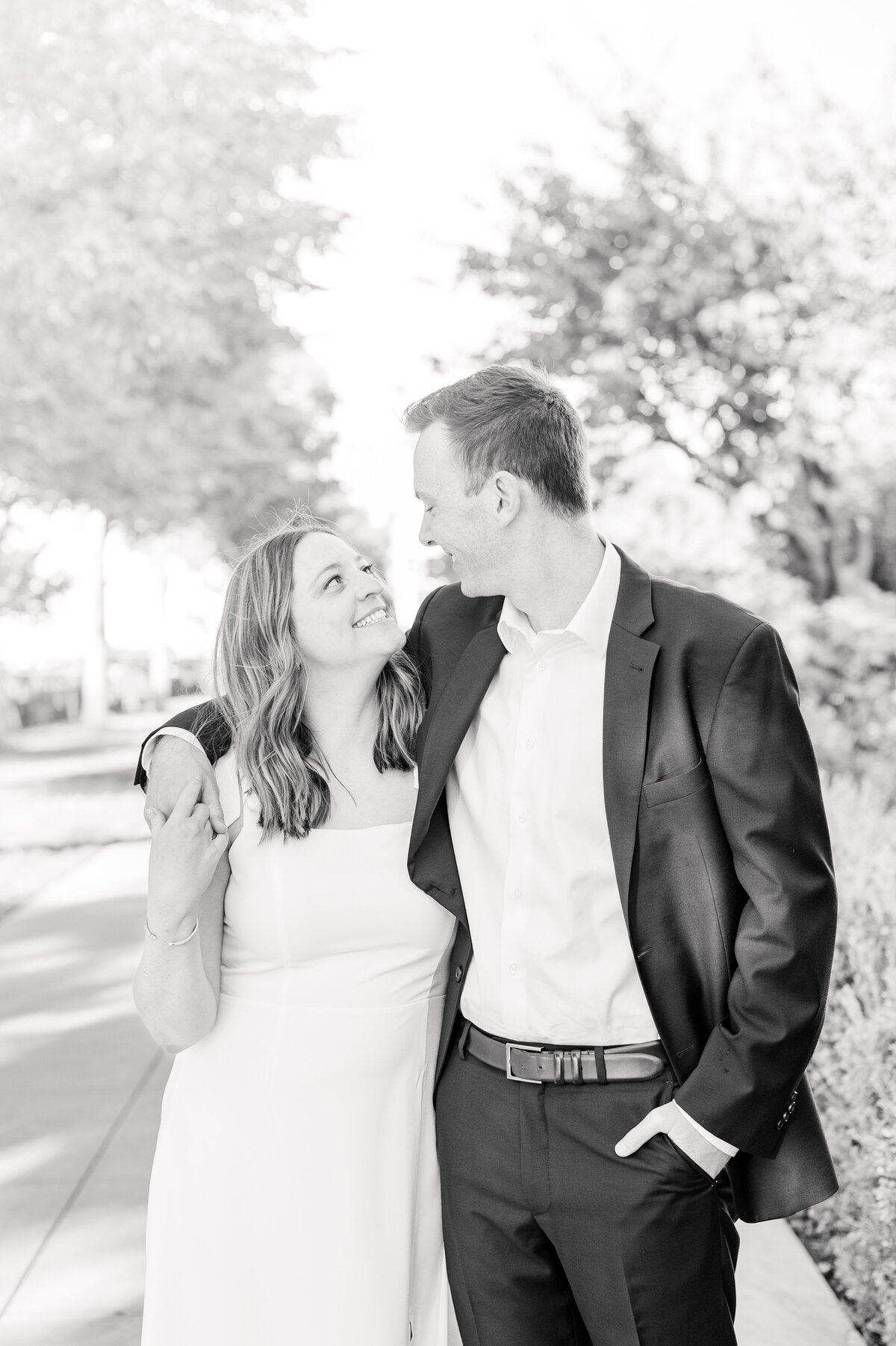 couple walking with arms over each other in black and white