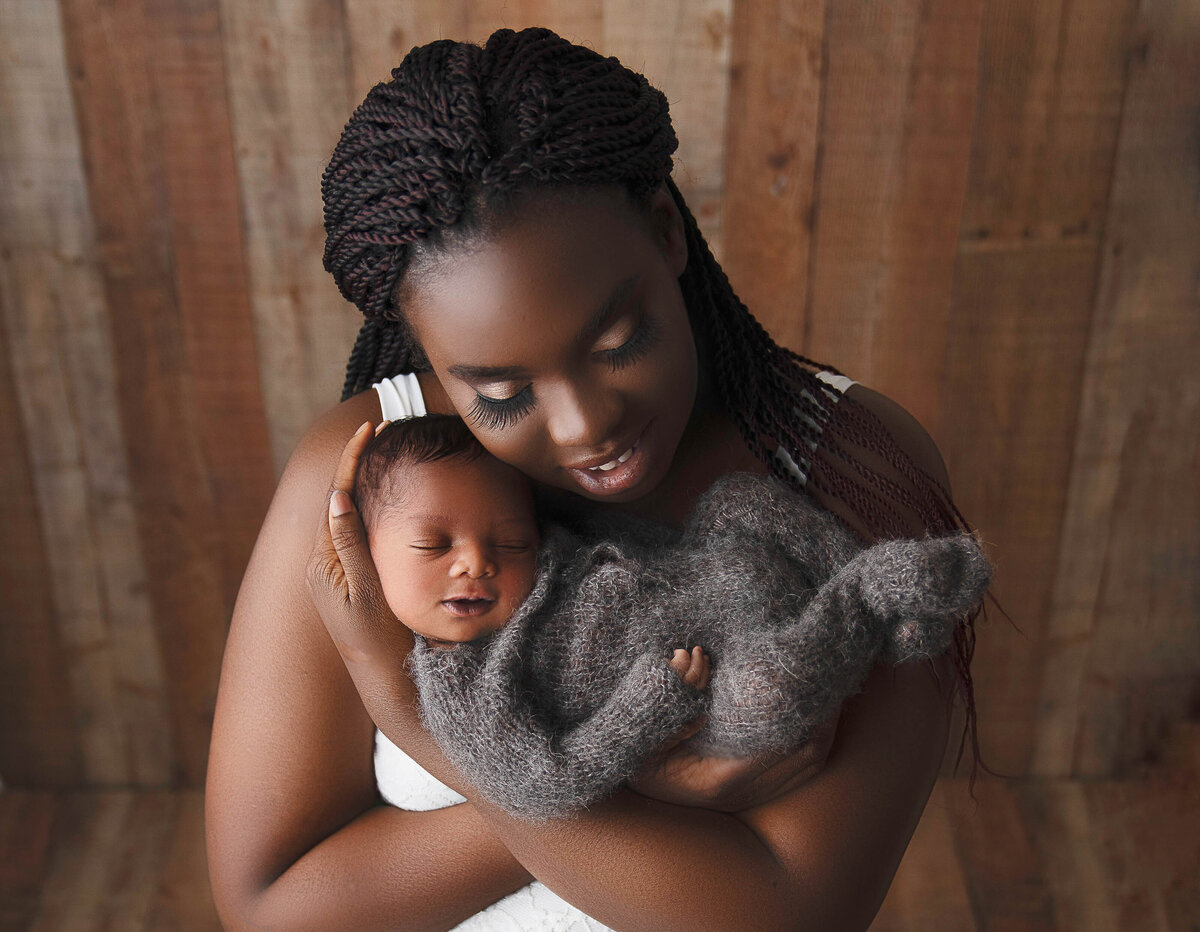 New mom holds her baby with her arms folded underneath him. Mom's cheek is resting atop of baby's head. Captured by Bryn Mwar Philadelphia and Main Line photographer Liza Nicole.