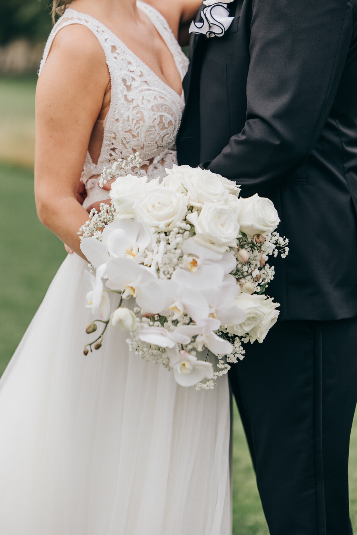 A close up of a white wedding bouquet while a bride and groom are embracing
