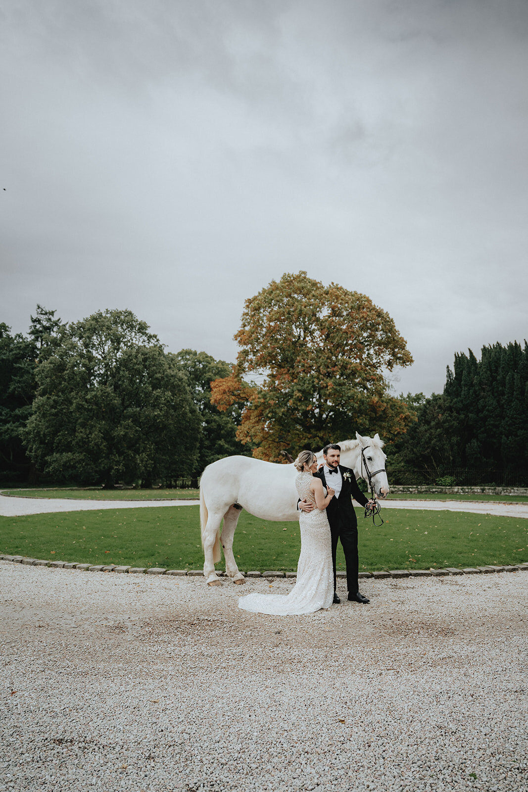 Bride looking at husband in front of white horse