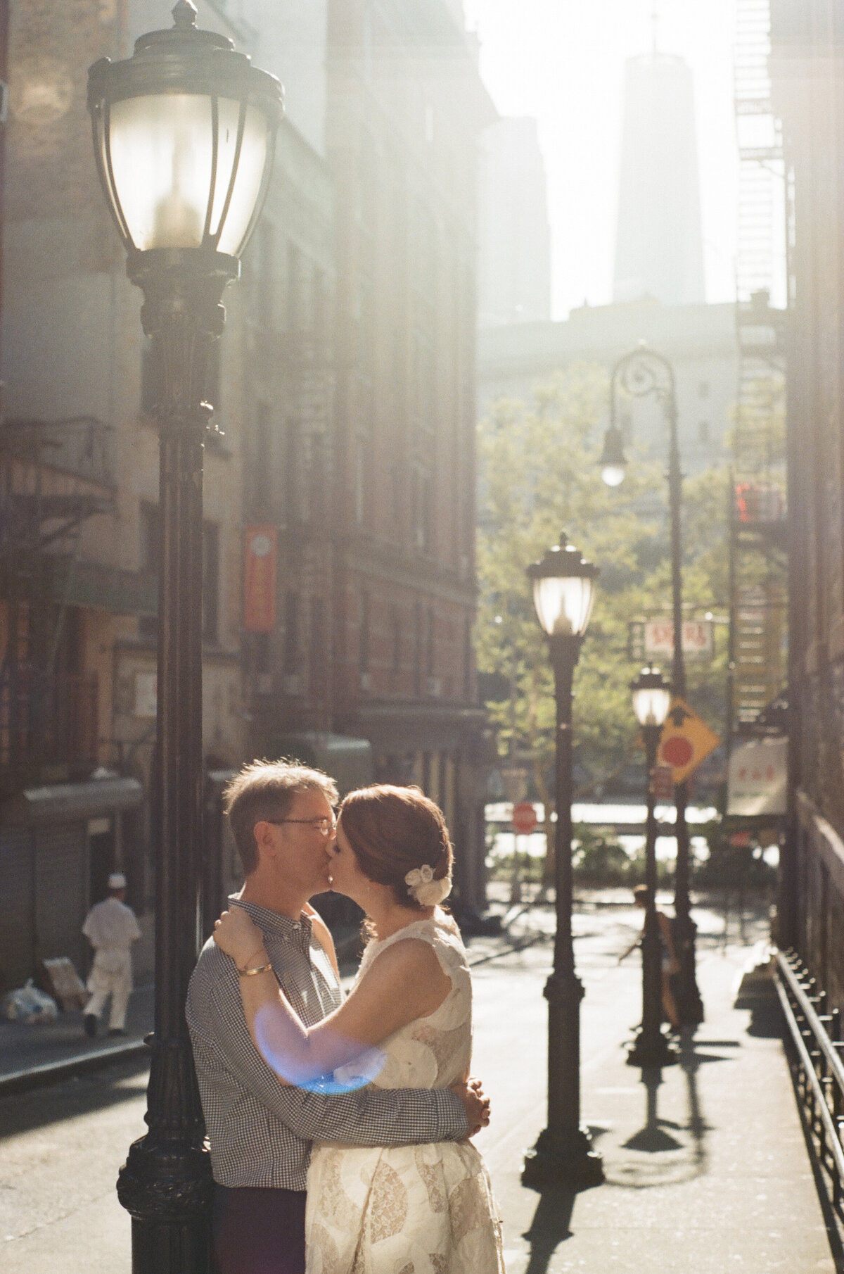 A couple leaning up against a lightpost kissing.