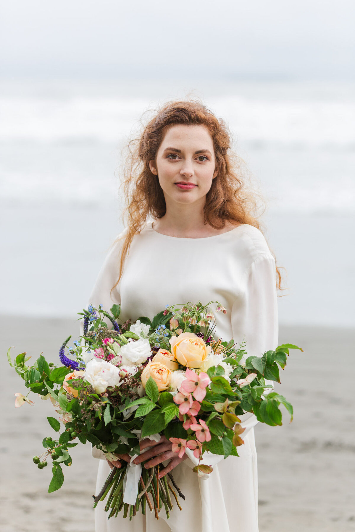 Bride-at-elopement-on-Ruby-Beach-near-Seattle-WA-with-giant-wild-bouquet-photo-by-Joanna-Monger-Photography