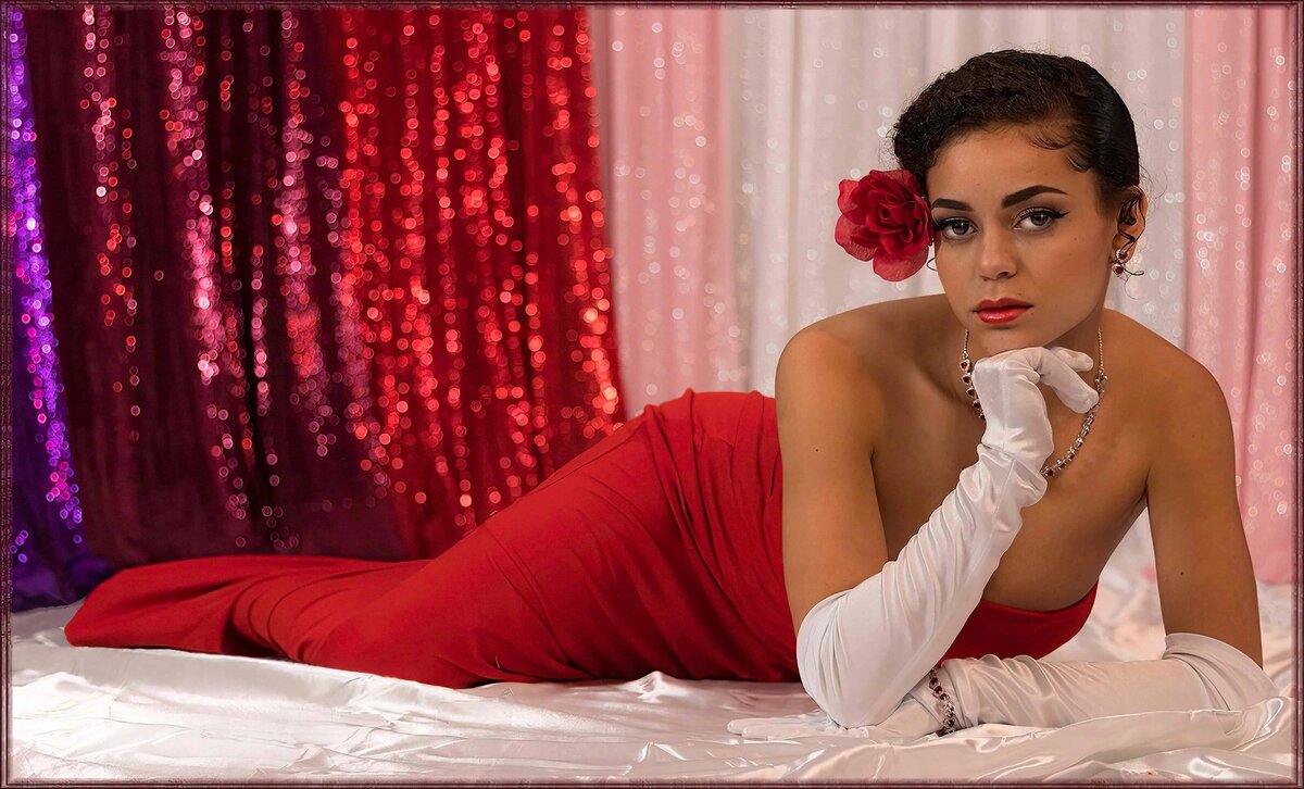 Lady in red with white gloves lying on satin