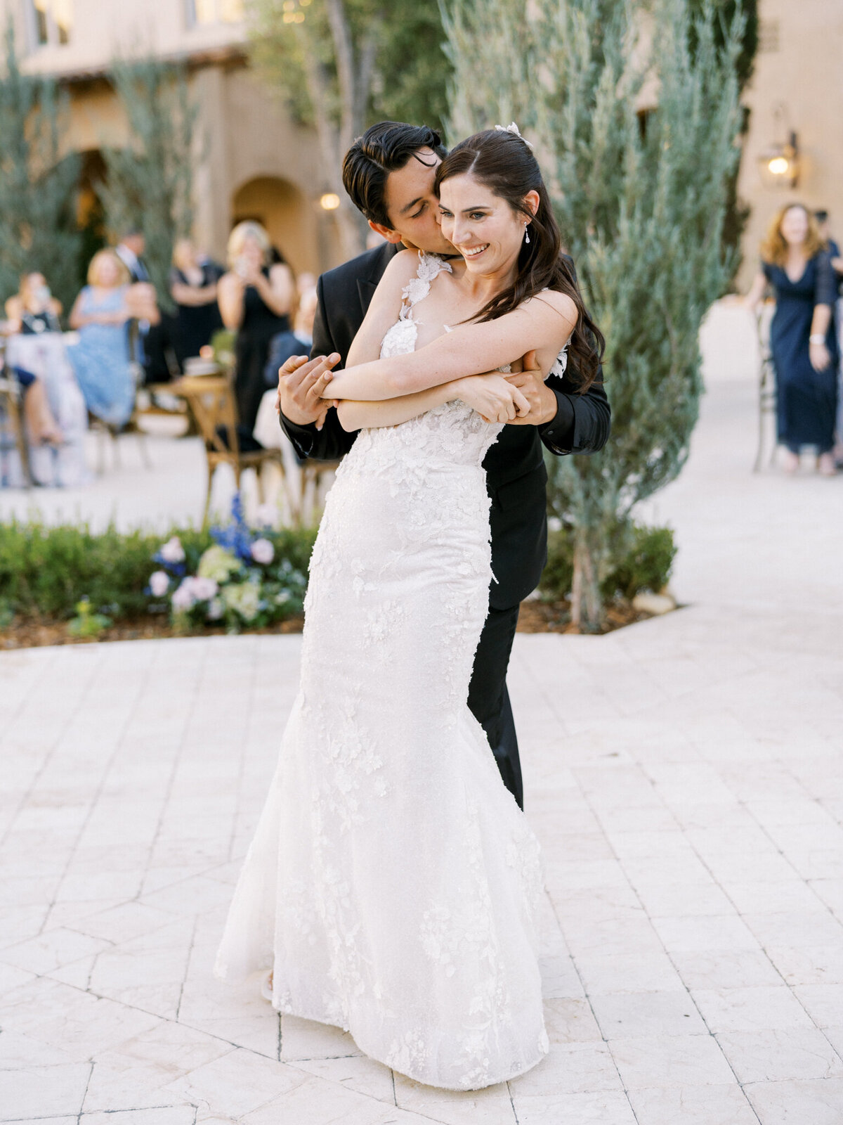 Sweet newlywed embrace during golden hour—pure joy and romance at a vineyard wedding celebration.