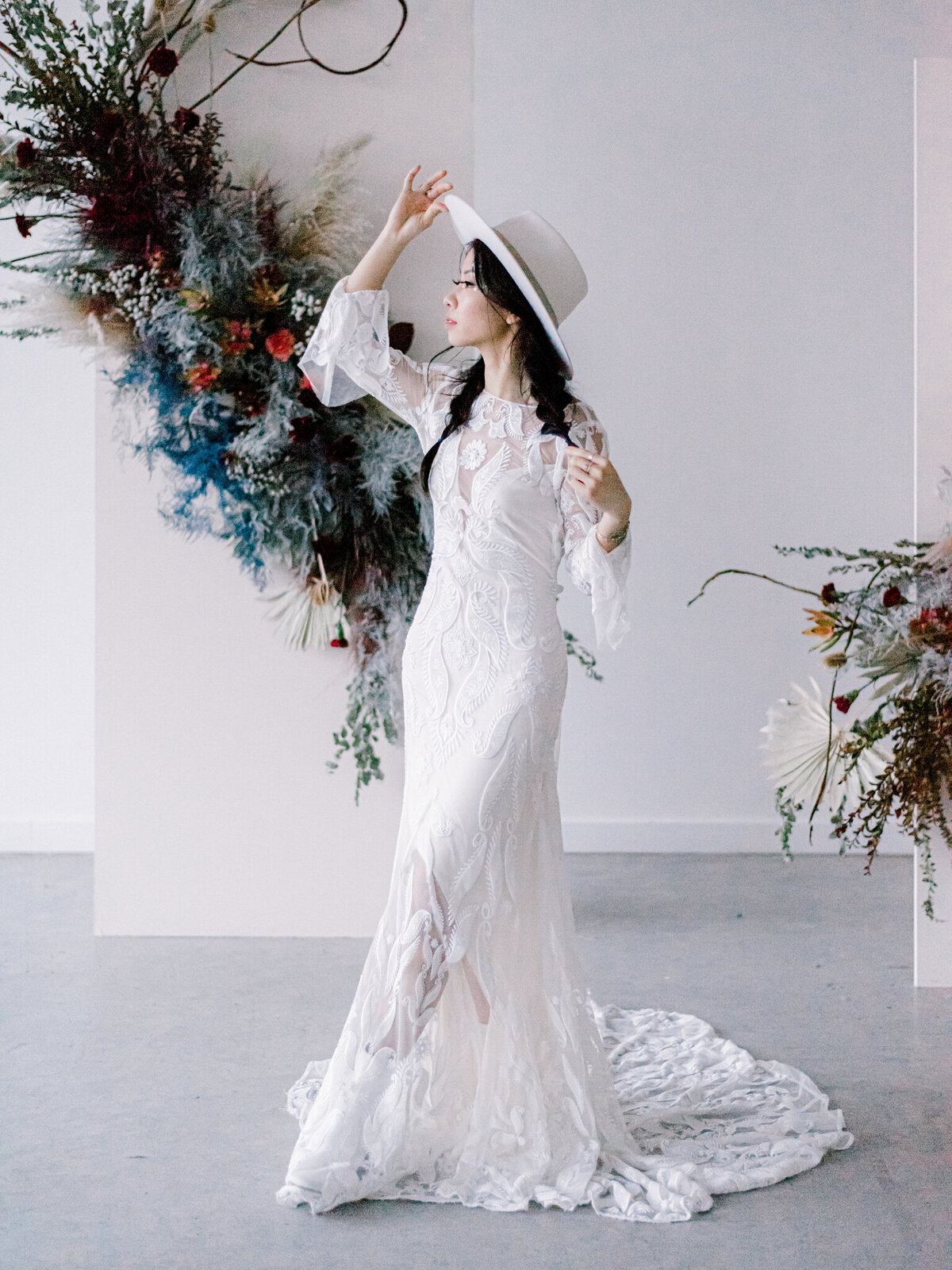 Boho inspired bride wearing bateau wedding dress with lace, long-sleeved with trendy wedding hat, captured by Julie Jagt Photography, fine art wedding photographer in Vancouver, BC. Featured on the Bronte Bride Vendor Guide.
