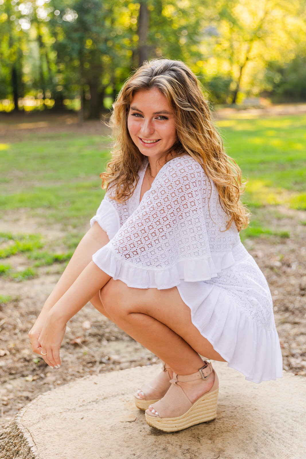 close up portrait of senior girl squadding down and looking at the camera over her shoulder in an Atlanta park during photoshoot