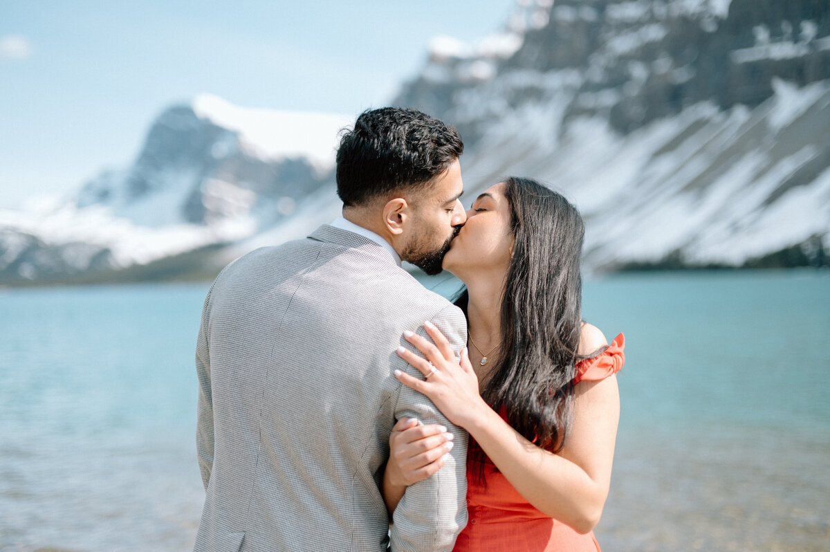 Couple kissing at Bow Lake overlook with sweeping glacier and valley views.