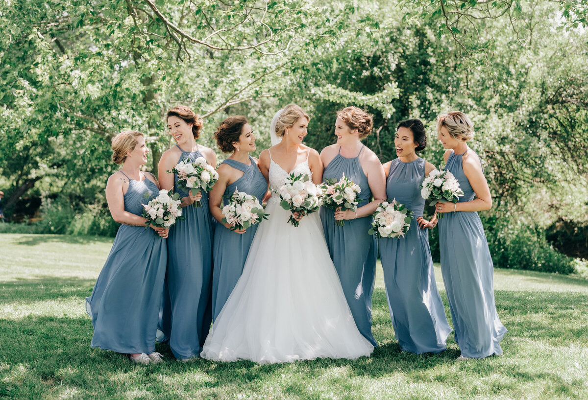 Bride and bridesmaids holding beautiful white and pink rose bouquets with eucalyptus during outdoor wedding portraits