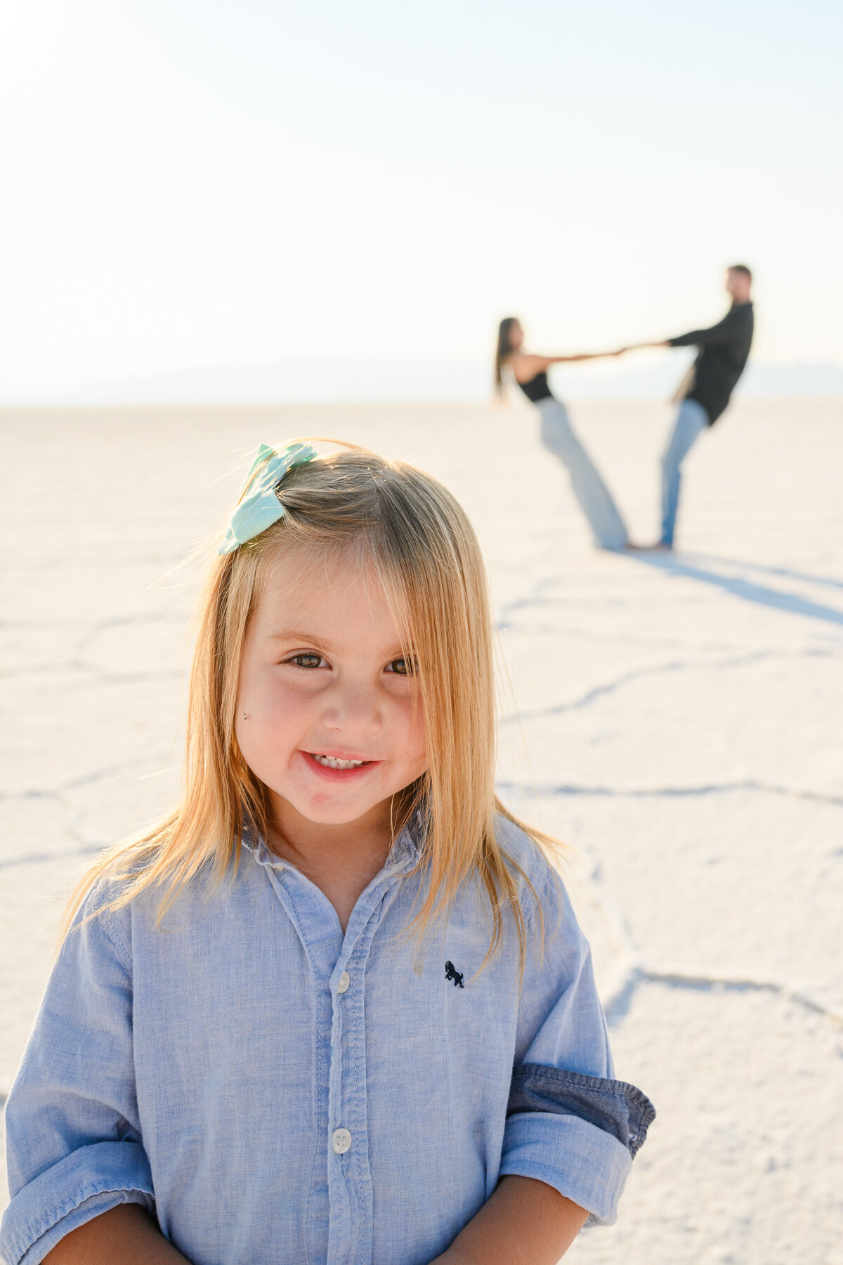 little girl poses with parents in background for a candid family photo in salt flats utah 