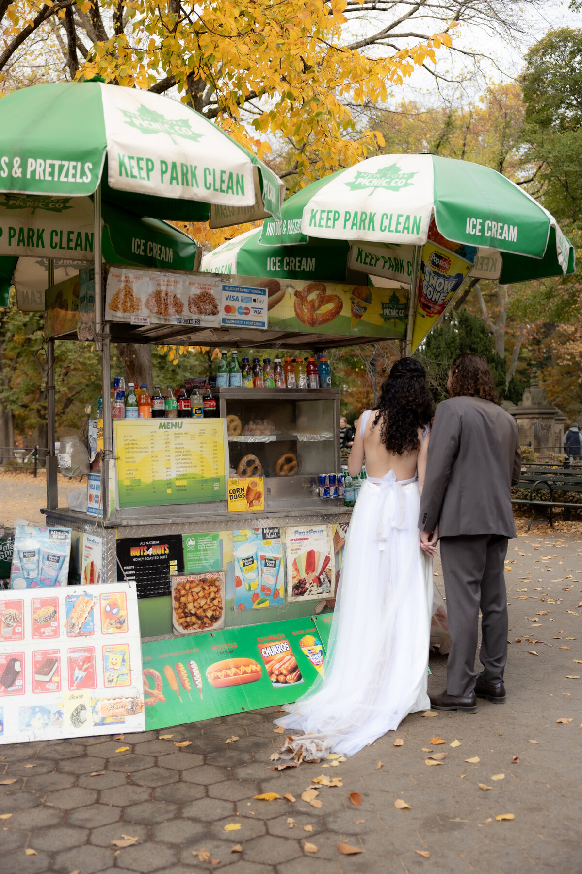 The bride laughing joyfully while holding her bouquet among autumn leaves in Central Park.