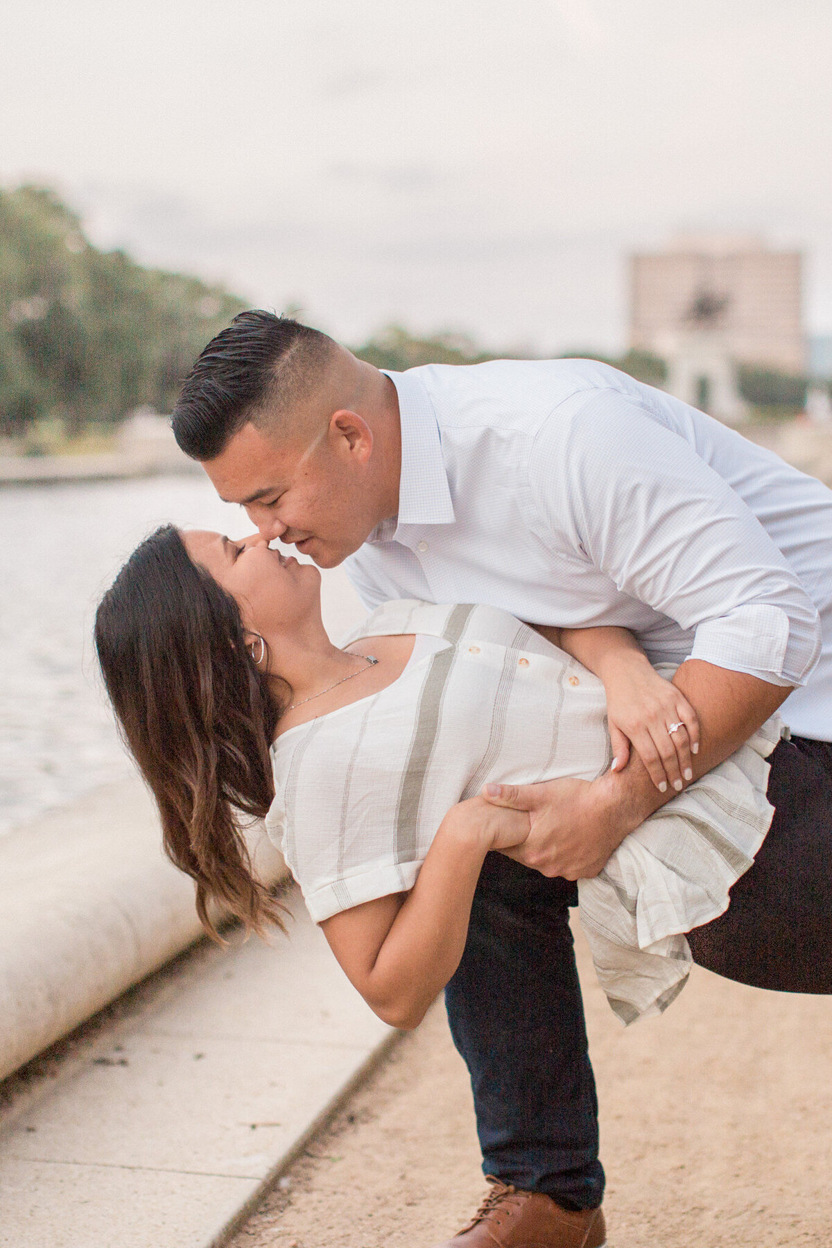 A man dips his bride to be in front of the water feature at Hermann Park