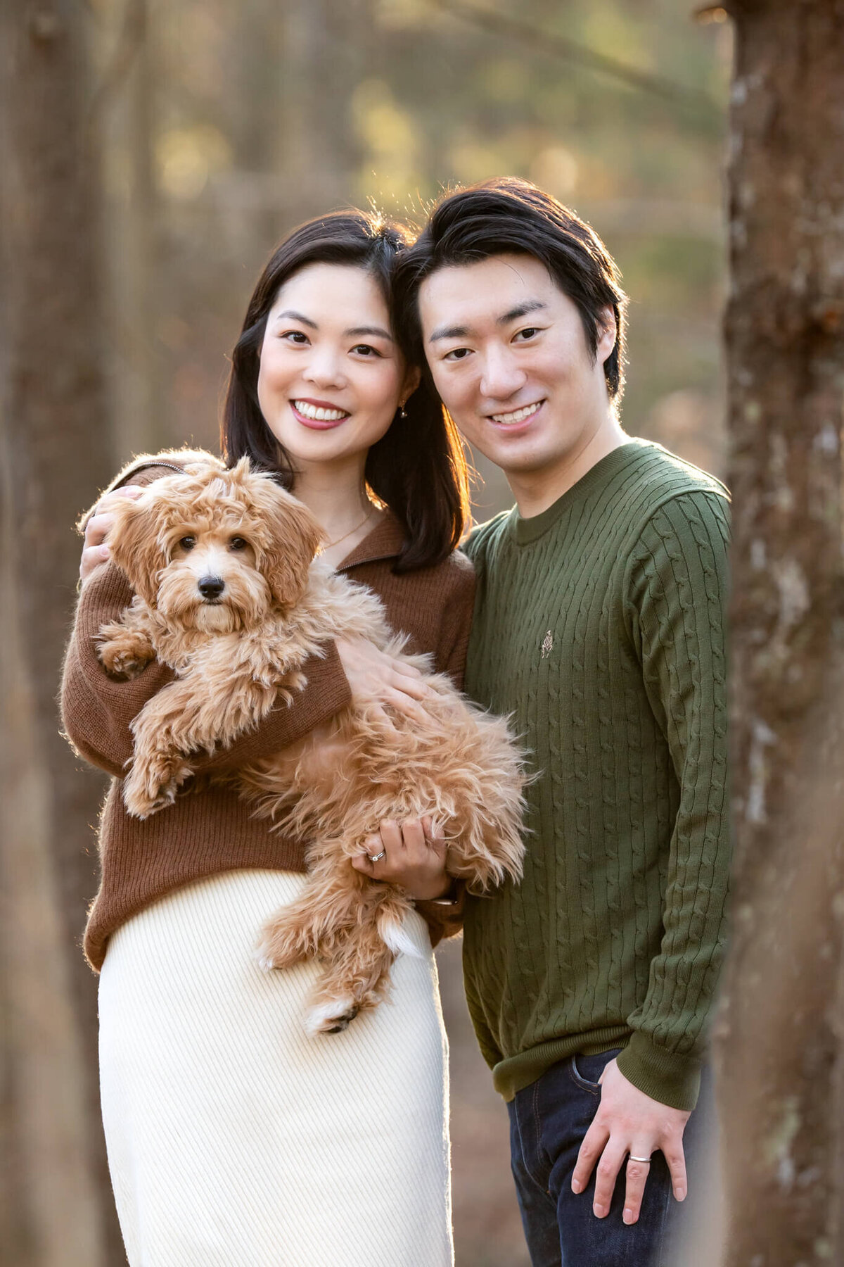 Gorgeous couple standing  in the forest with their Golden Doodle puppy