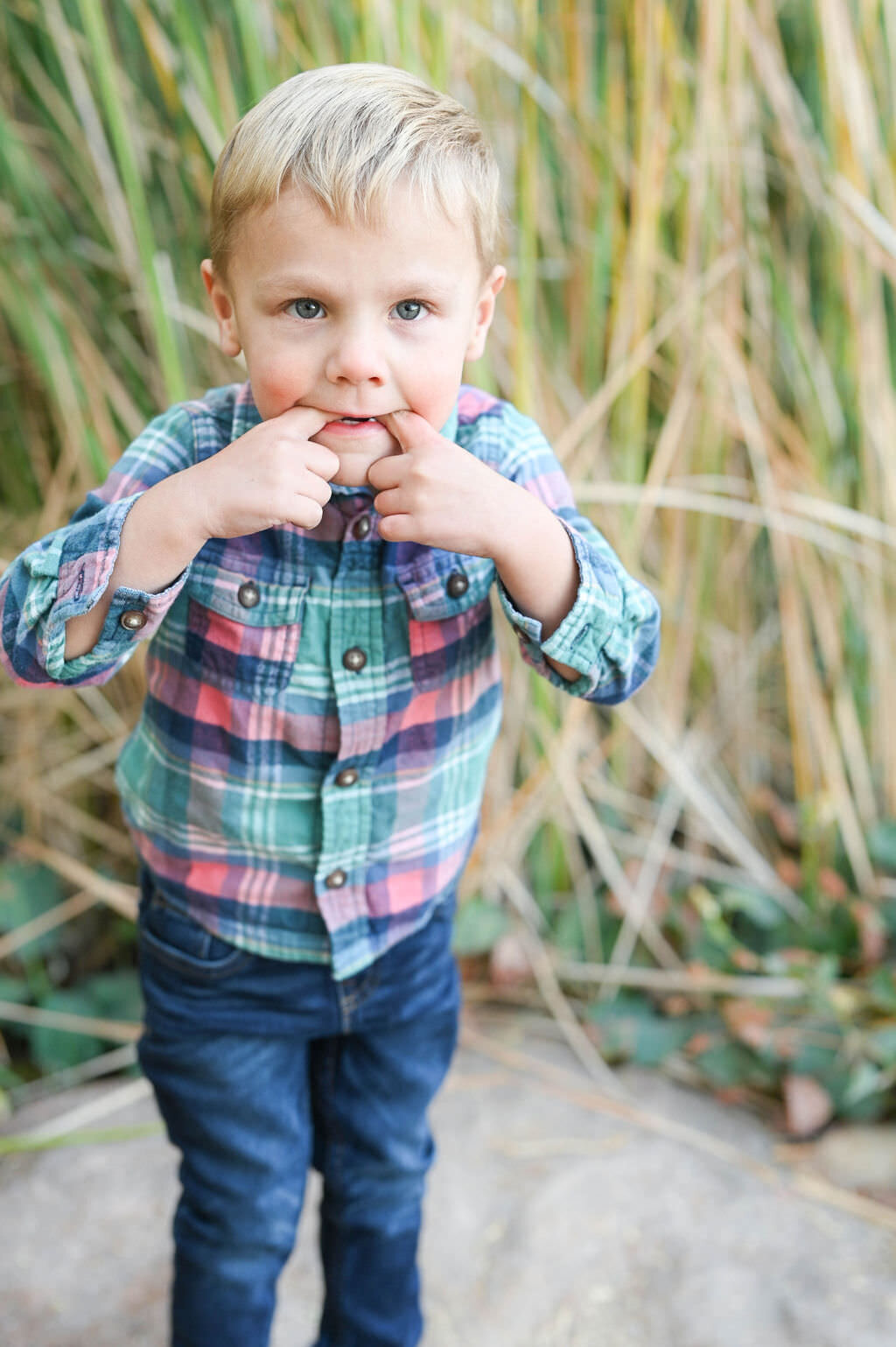 A small boy with his pointer fingers in his mouth.