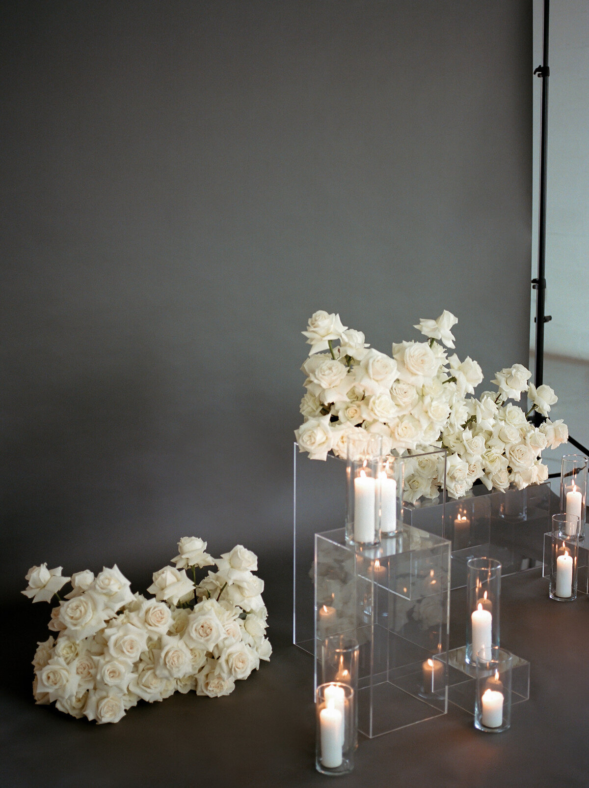 abundant white roses, candles, clear pillars with gray studio backdrop, film brand photographer in Michigan