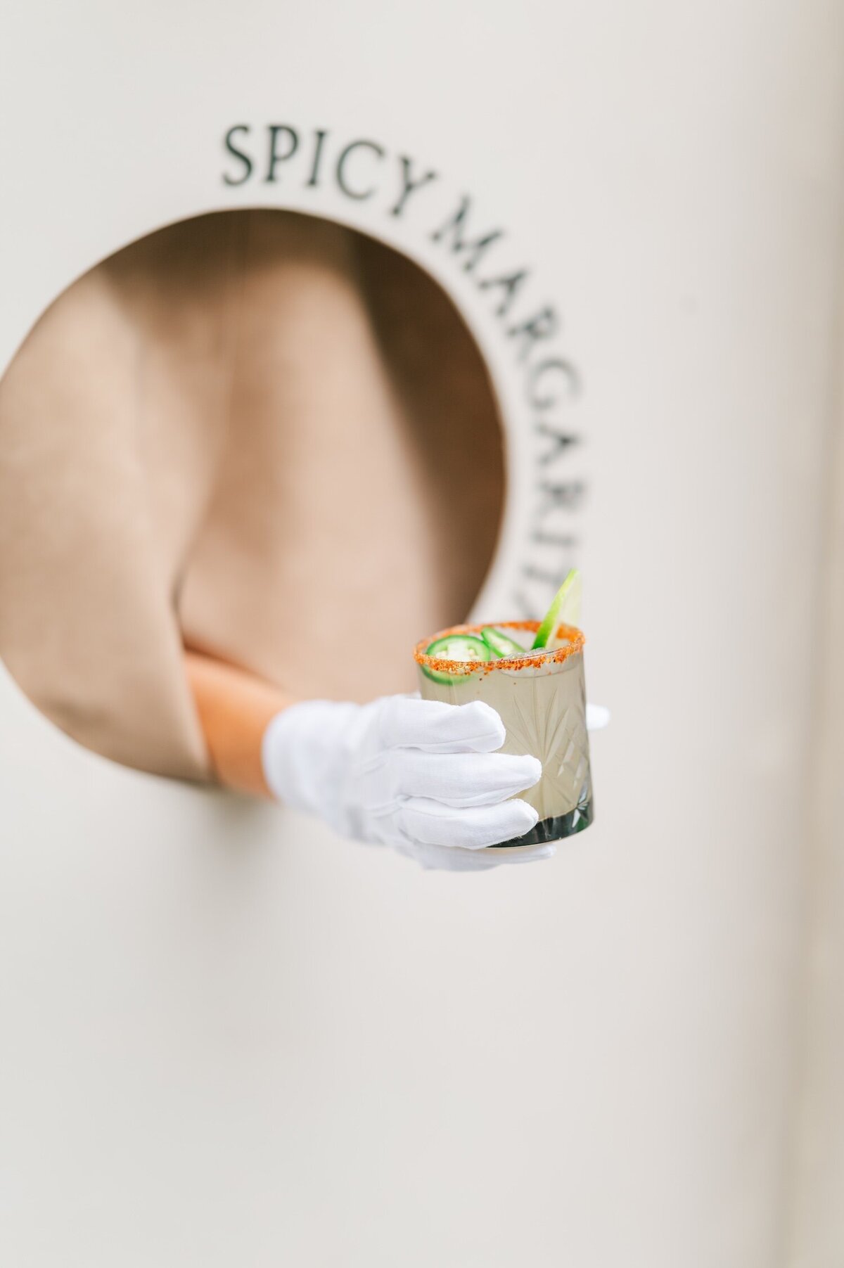 A hand with a white glove holding a spicy margarita out of a seating chart. 