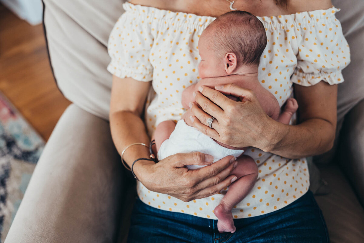 a close up photo of a baby held against his mother's chest with her hands on his back in their south park home in San Diego, CA.