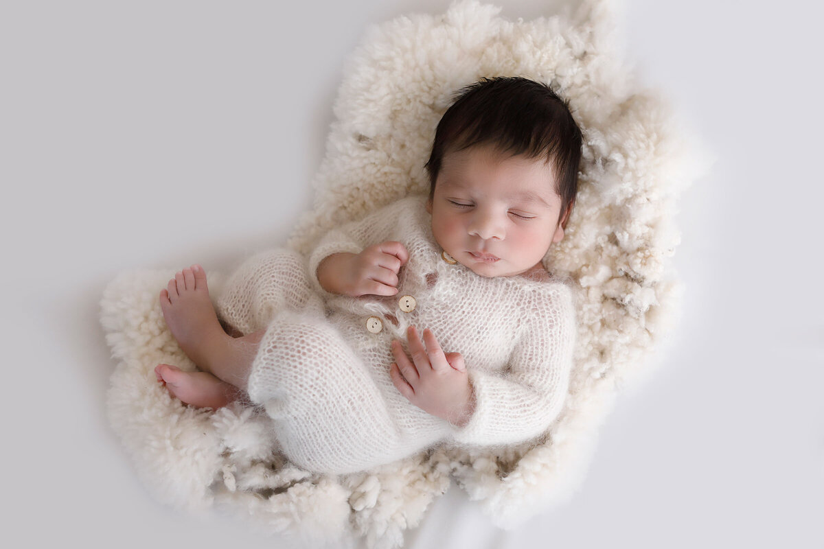 Baby-boy-sleeping-on-a-white-sheep-skin-for-his-newborn-photoshoot