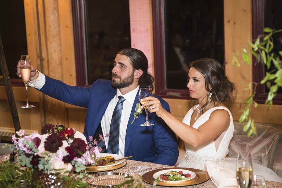 A bride and groom raise their champagne glass in a toast.
