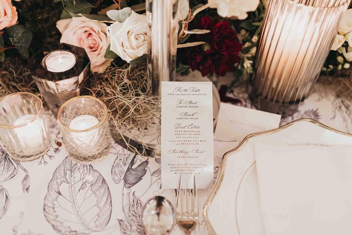 Menu, candles, linens, and plates for a wedding table set up.