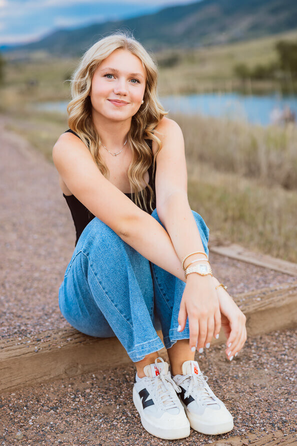 Girl poses on stairs with lake behind her.