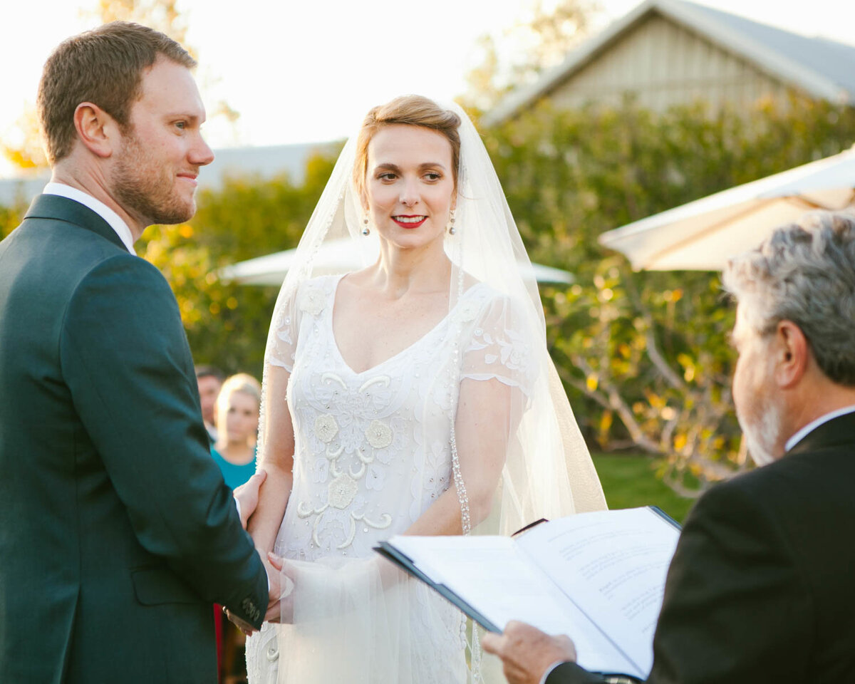 Couple looks at the officiant smiling as they listen
