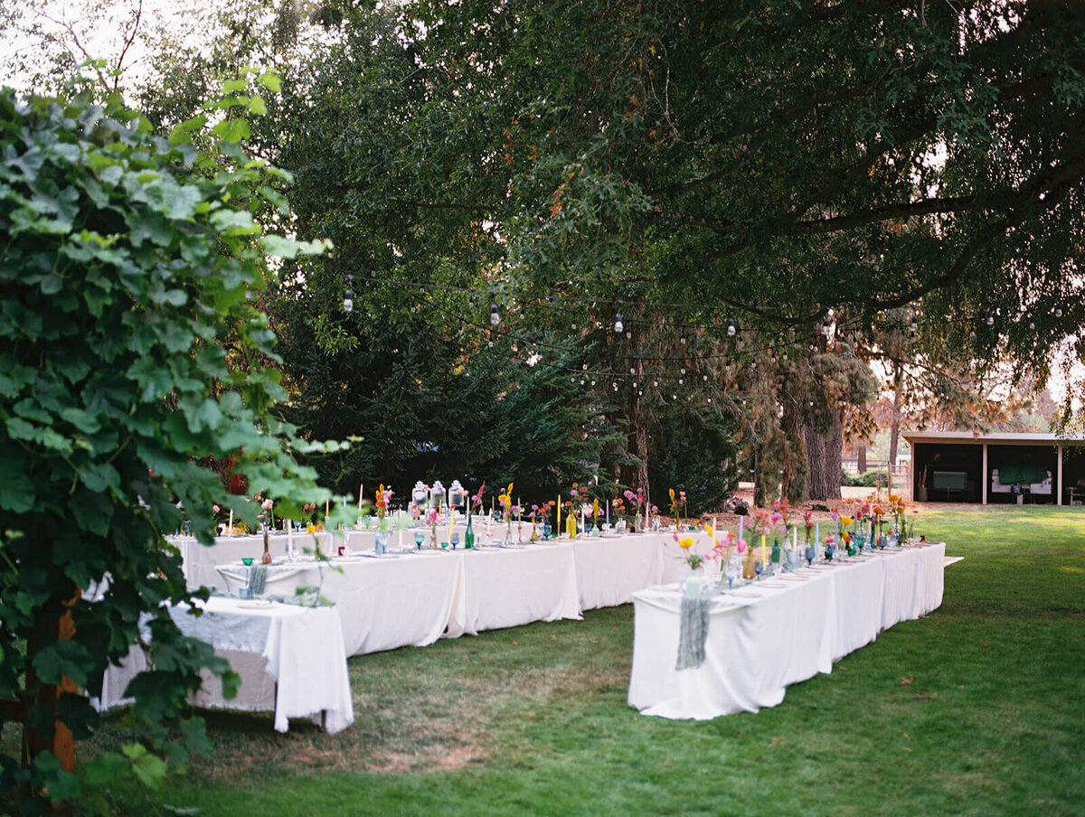 An outdoor backyard wedding reception shows tables ready for guests. 