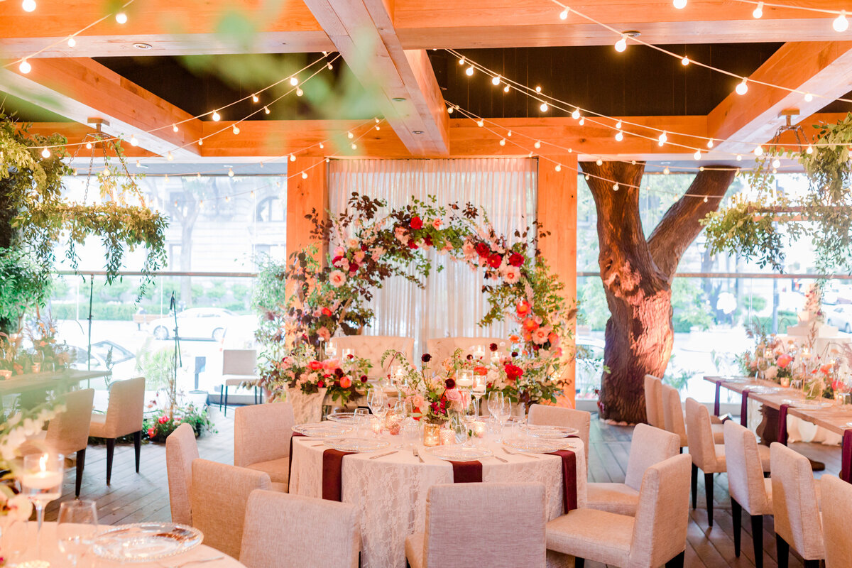 A lush arch of pink flowers and airy greenery frame a sweetheart table at Restaurant Beatrice. 