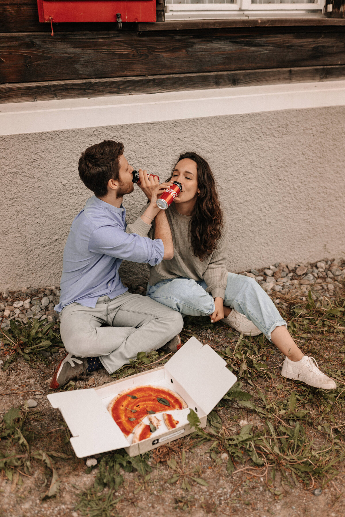 Liebespaar mit Pizza vor einer alten Bahnstation