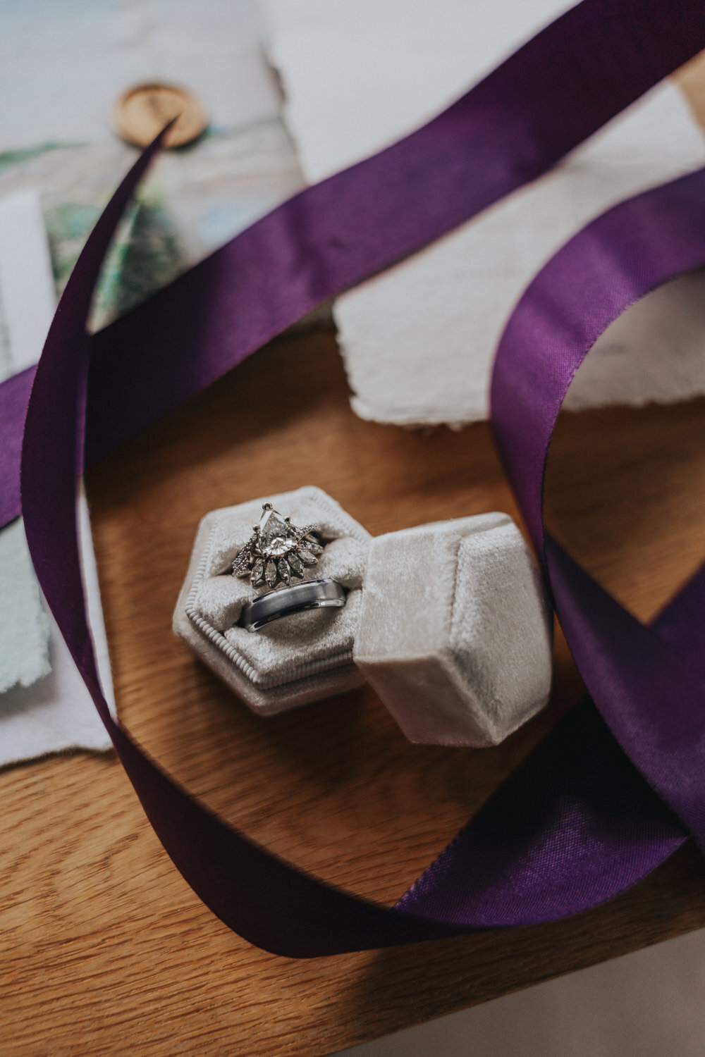 Two wedding rings sit in a box atop a wooden table 
