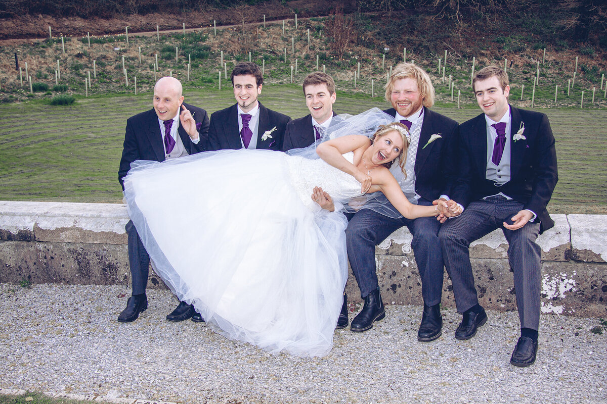 pro-story-photography_bride-lying-on-groom-lap-accompanied-by-male-party_kitley-house_yealmpton_devon