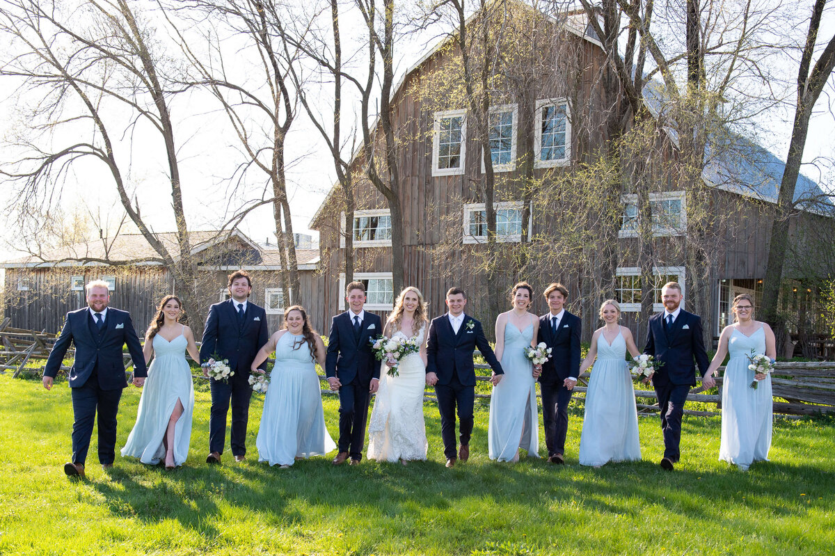 a photo of a  bridal party walking with the Stonefields Loft in the background
