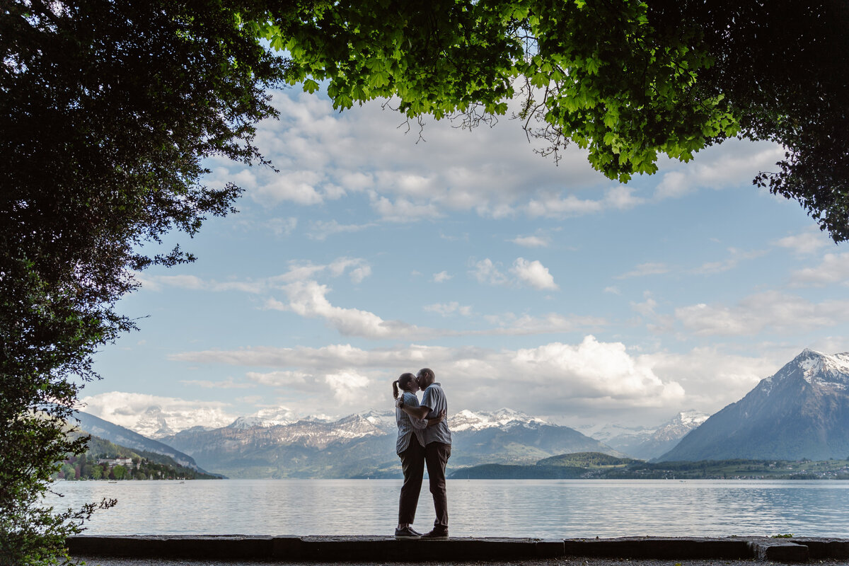 A couple kissing with trees framing the image