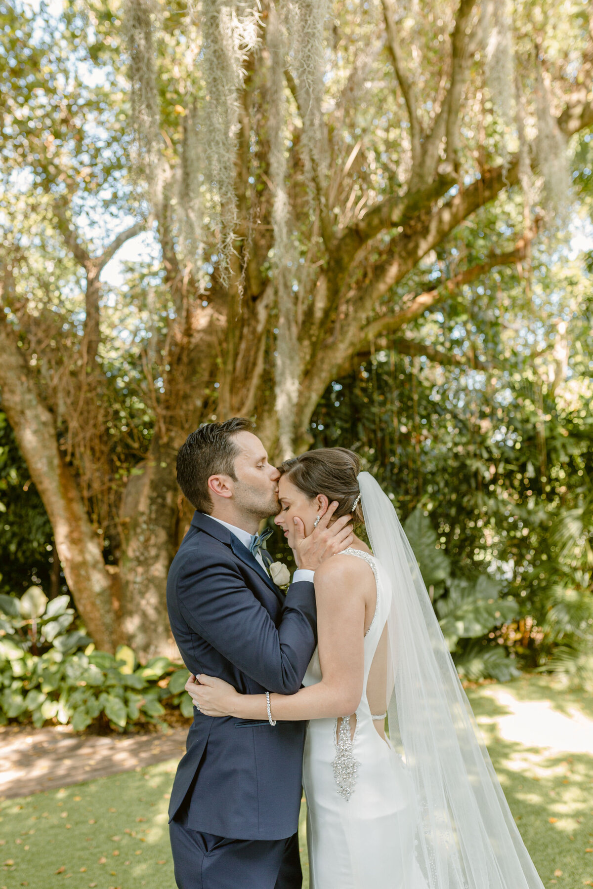 Bride looks downwards as her hair blows in her face wearing wedding gown