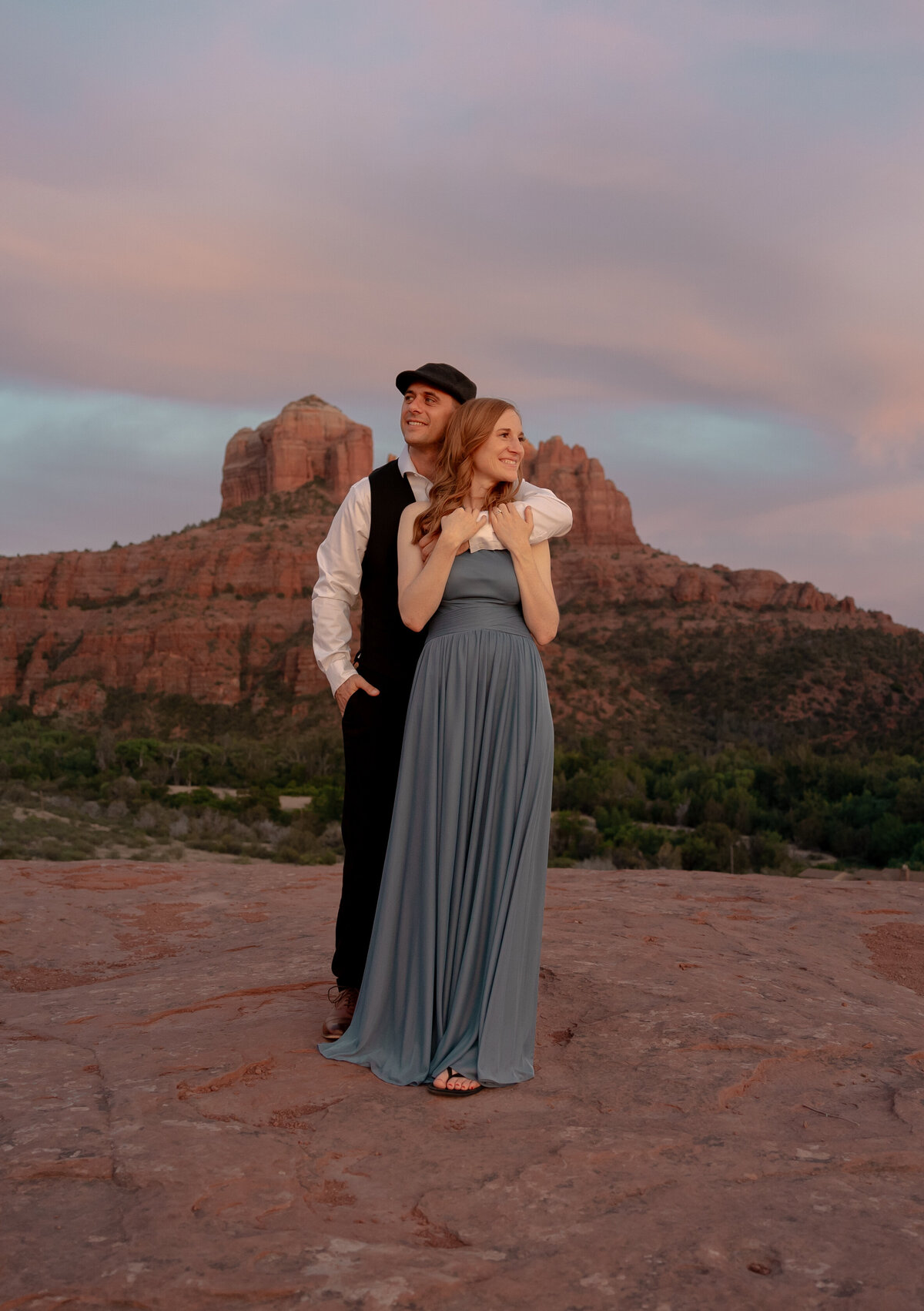 Couple standing against red rock backdrop during Sedona engagement session
