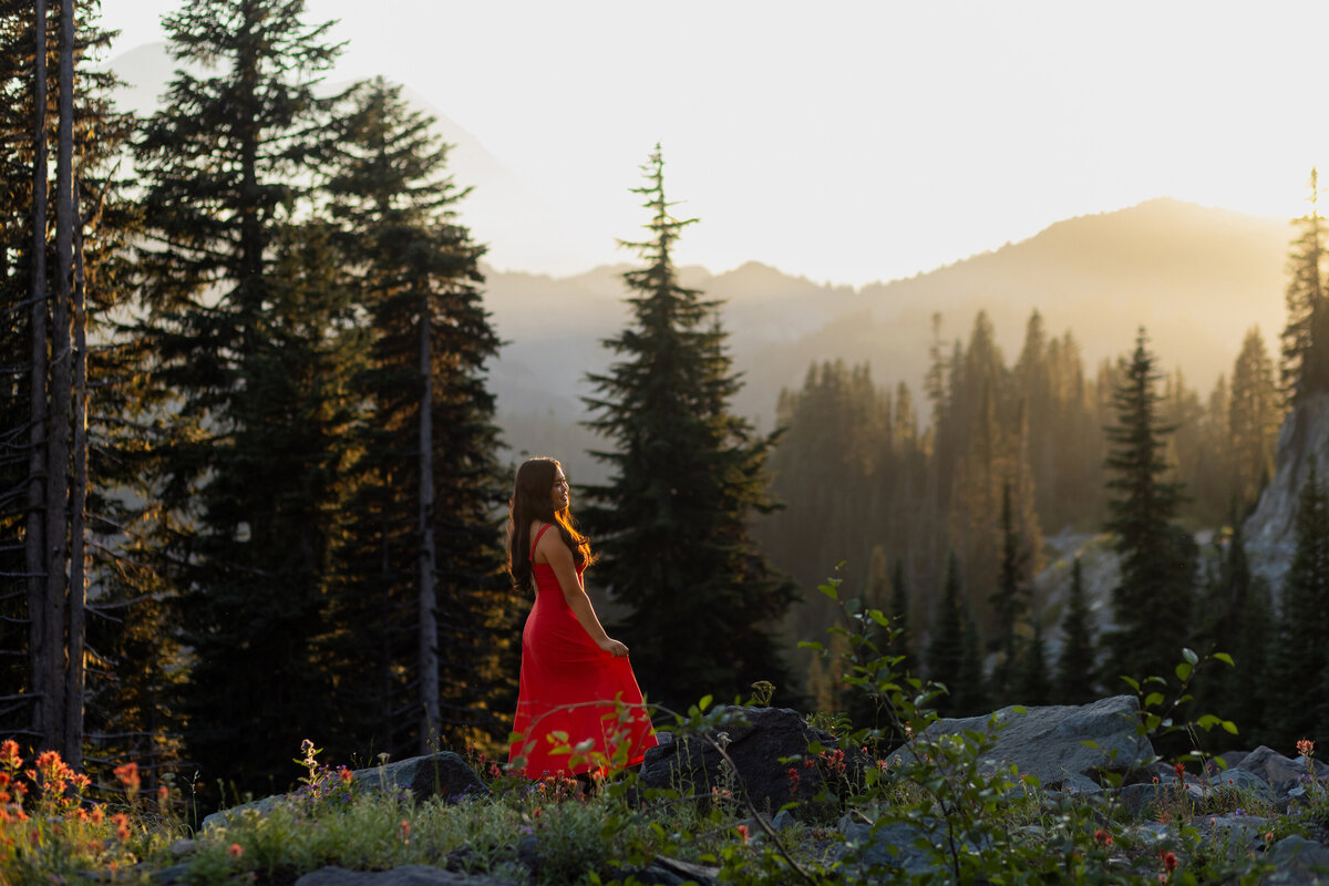 wildflower sunset and mount rainier in the backdrop with senior girl in red dress looking into the distance