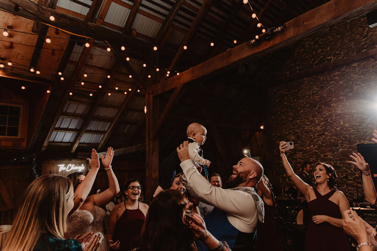 A wedding guests holding up a baby at a reception 