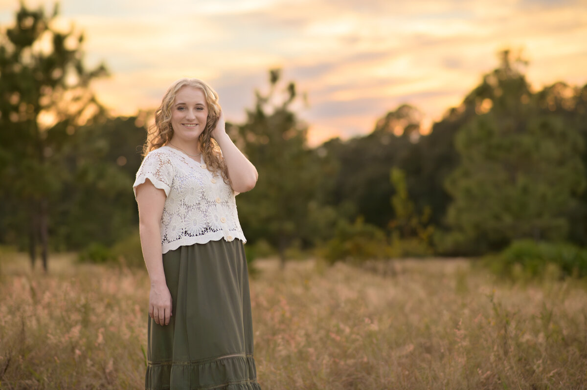 high school senior girl in long skirt and white top in field with tall grass at sunset in Orlando